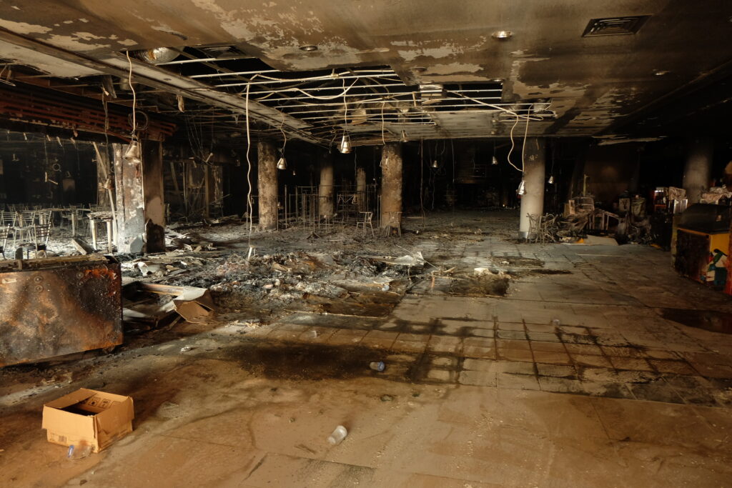 Why a Cheap Replacement Cost Estimate Could Cost You More Than It Saves burnt interior shows devastation after fire in commercial building, revealing charred debris and structural damage with somber atmosphere.